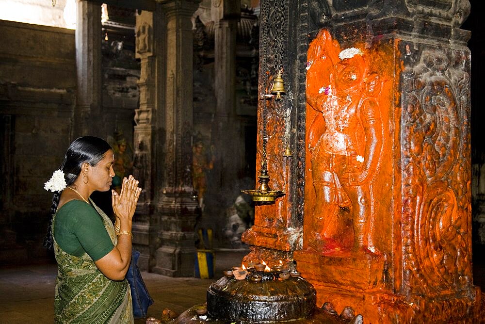 Female worshiper praying beside a shrine, Meenakshi Temple, Madurai, Tamil Nadu, India