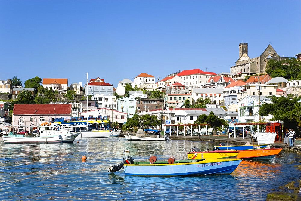 Water taxi boats moored in the Carenage harbour of the capital city of St. Georges, with the roofless cathedral damaged in Hurricane Ivan on skyline, Grenada, West Indies, Caribbean, Central America