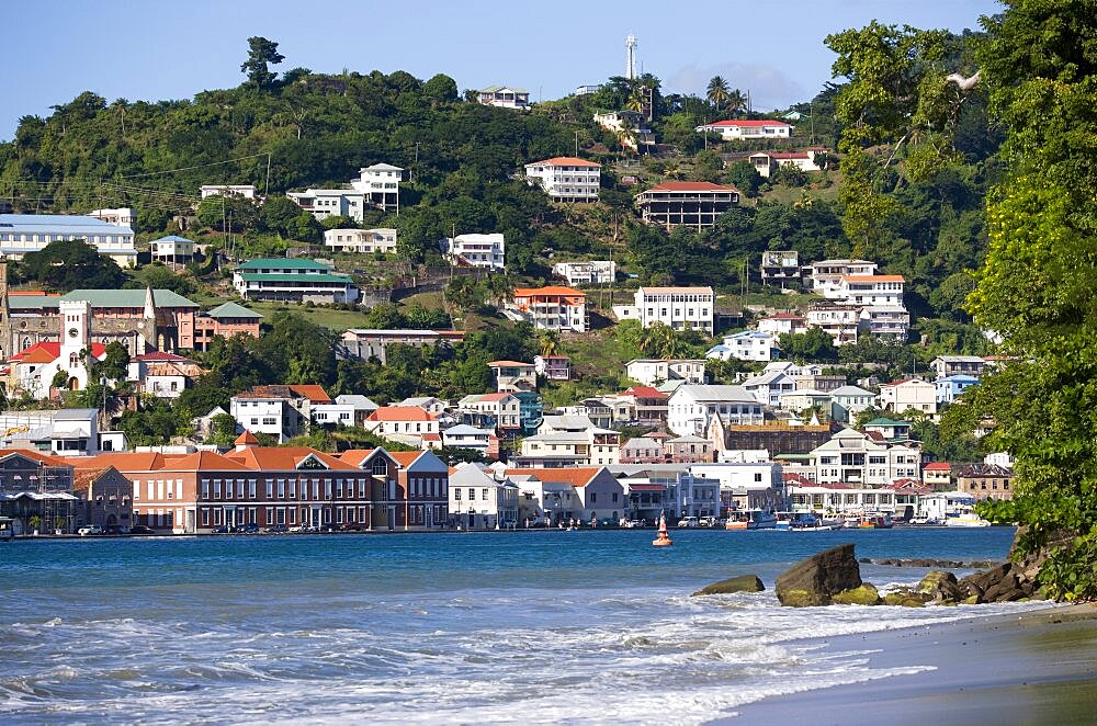 The hillside buildings and waterfront of the Carenage in the capital St Georges seen from Pandy Beach beside Port Louis Marina, Caribbean