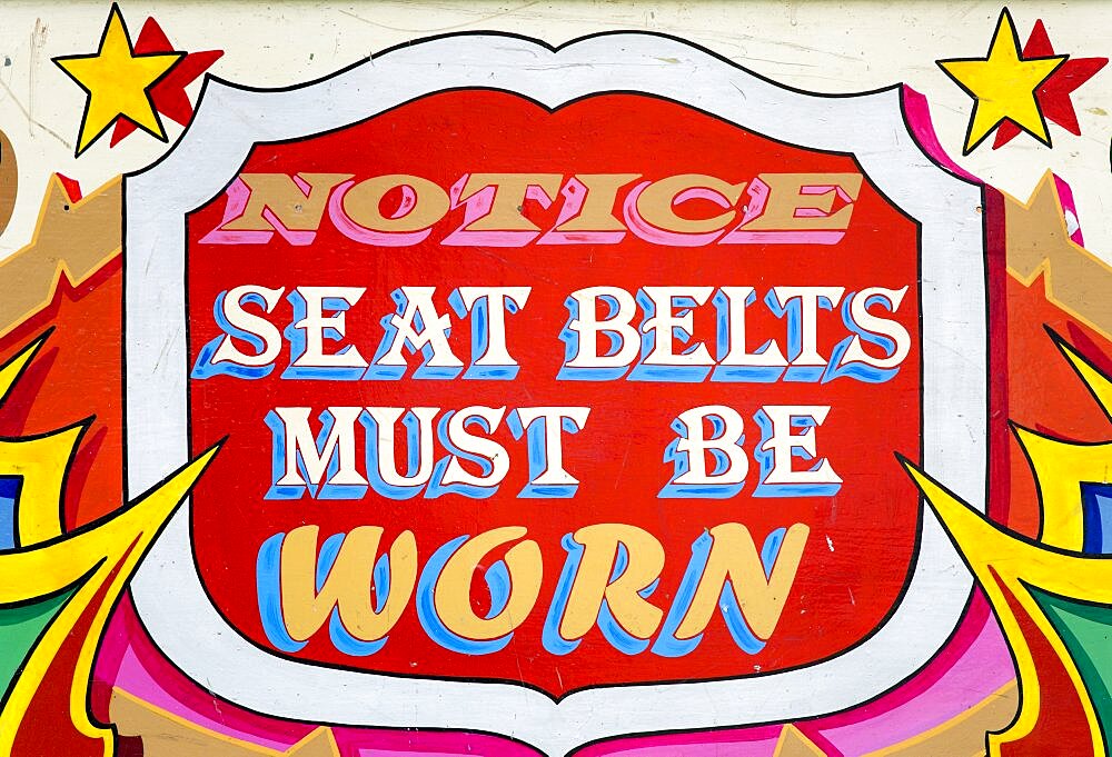 Findon village Sheep Fair Colourful red sign on a fairground ride that reads Notice Seat Belts Must Be Worn, United Kingdom