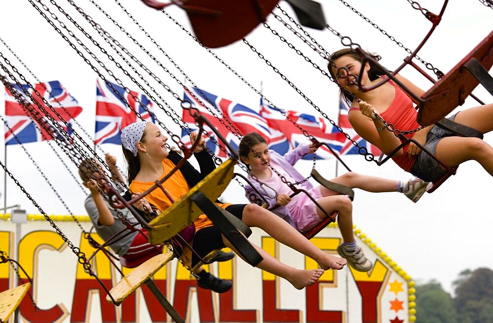 Findon village Sheep Fair Four children in motion riding on a swing carousel, United Kingdom