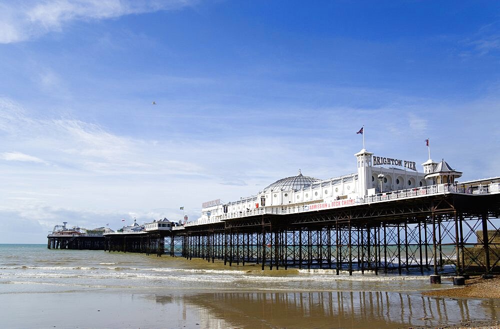 England, East Sussex, Brighton, The Pier at low tide with shingle pebble beach in foreground