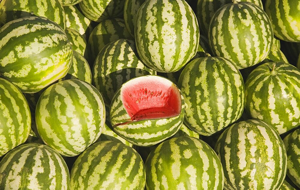 Turkey, Aydin Province, Kusadasi, Fresh watermelon on sale at town produce market with central fruit cut open to show red flesh and seeds