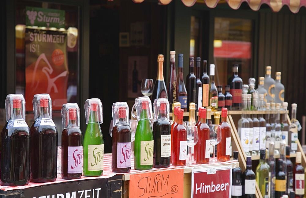 Austria, Vienna, The Naschmarkt, Display of Federweisser, wine in the fermentation stage, known as Sturm in Austria, line of bottles with tasting glasses
Due to the carbonic acid, Federwei?er tastes quite refreshing, not unlike a grape lemonade or a sweet sparkling wine