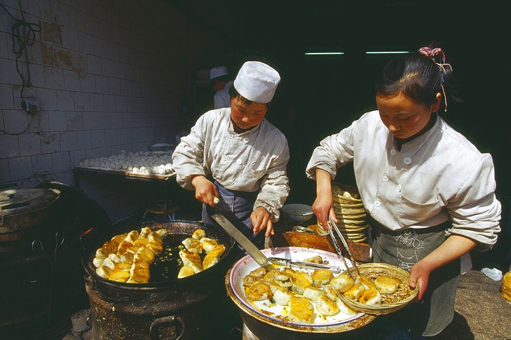 CHINA Shaanxi Province Xian Two cooks preparing dish of fried food.