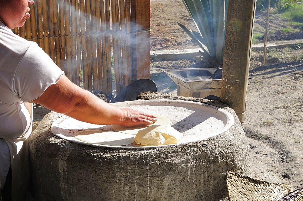 Woman making tortillas outside on traditional comal griddle, Oaxaca, Mexico