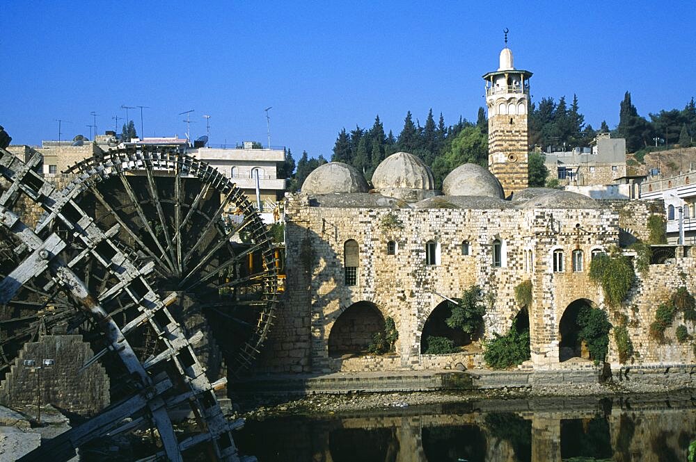 SYRIA Central Hama Wooden norias or waterwheels on the Orontes river and the Al Nuri Mosque dating from 1172 and built of limestone and basalt. Section of wheel in the immediate foreground.