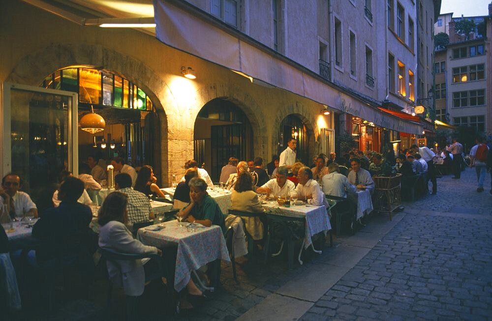 FRANCE Rhone Loire Rhone Lyon.  People eating at outside tables in street side restaurants in evening.