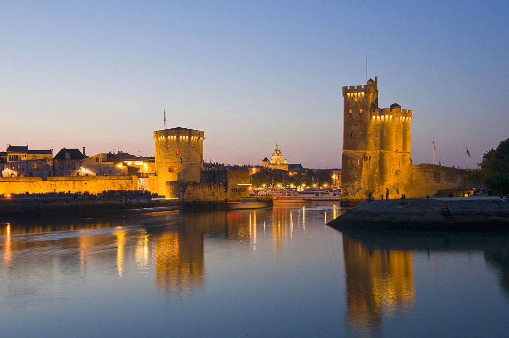 La Chaine and St. Nicholas towers at the entrance to the ancient port of La Rochelle at dusk, Charente-Maritime, France, Europe