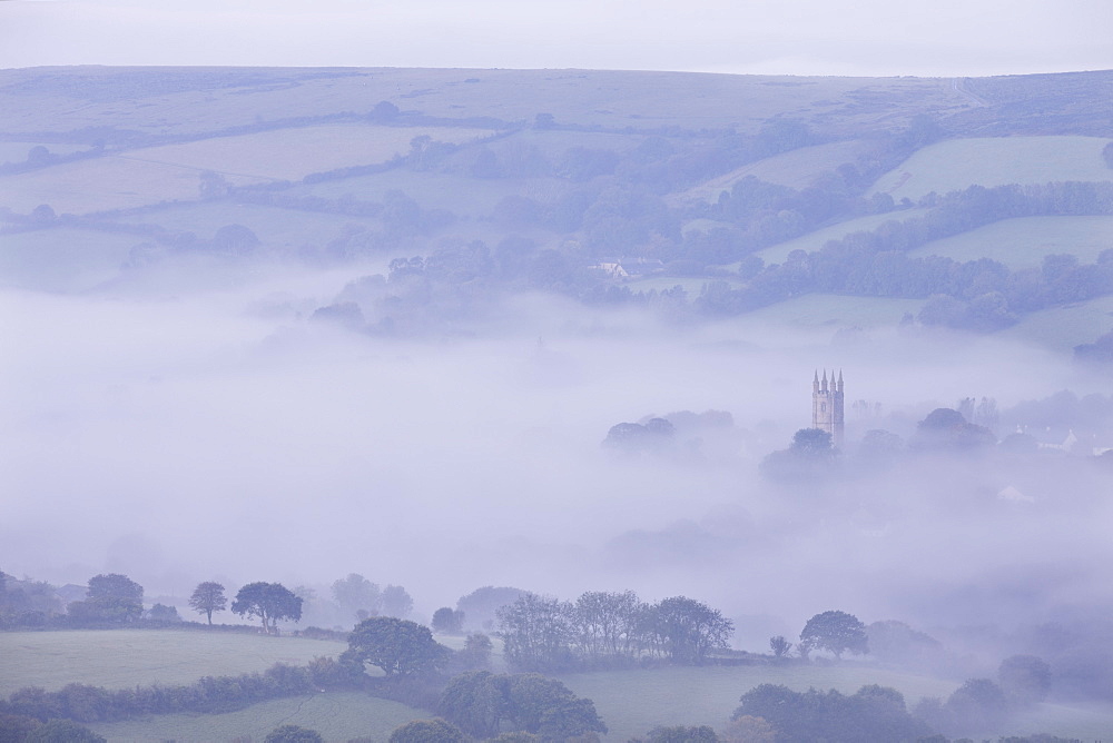 Morning mist swirls around the church tower of Widecombe in the Moor village on Dartmoor, Devon, England, United Kingdom, Europe