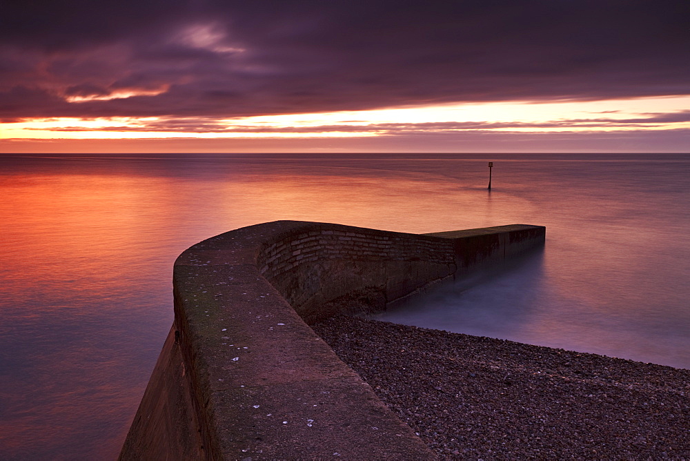 Stone jetty on Sidmouth beachfront at sunrise, Sidmouth, Devon, England, United Kingdom, Europe