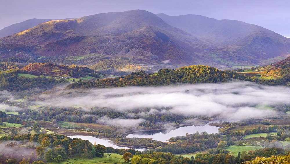 Autumn mist hangs above Elterwater with views beyond to Little Langdale and Wetherlam, Lake District National Park, Cumbria, England, United Kingdom, Europe 