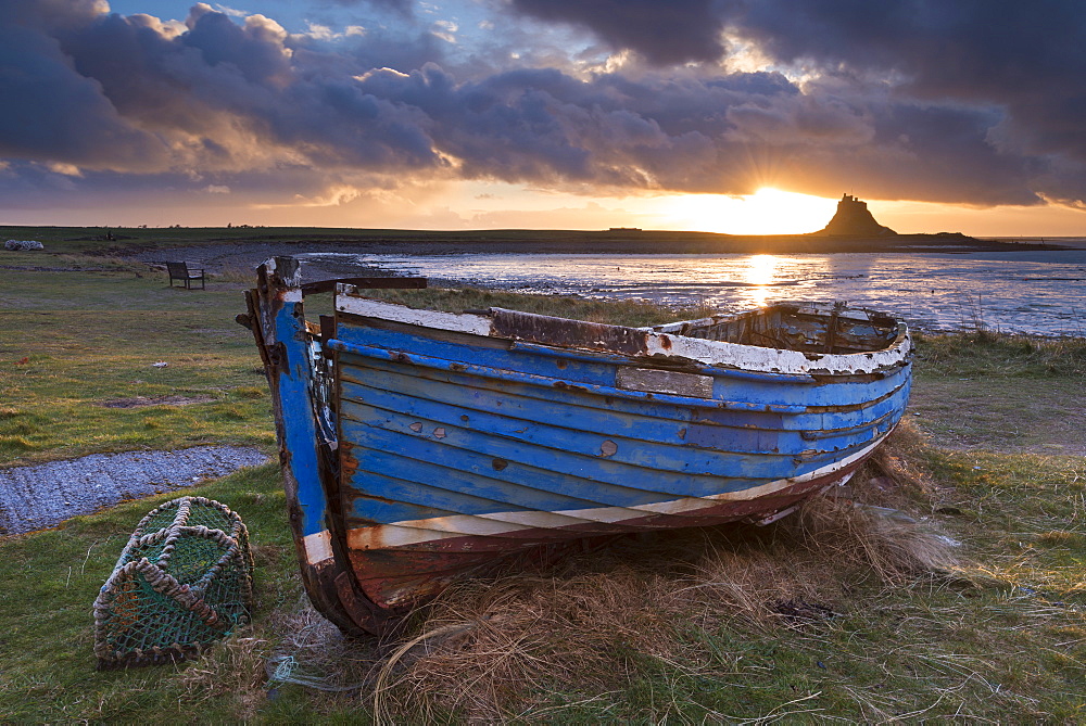 Decaying fishing boat on Holy Island at dawn, with Lindisfarne Castle beyond, Northumberland, England, United Kingdom, Europe