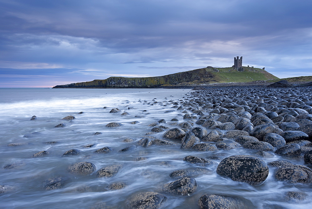 Dunstanburgh Castle above the boulder covered Embleton Bay, Northumberland, England, United Kingdom, Europe