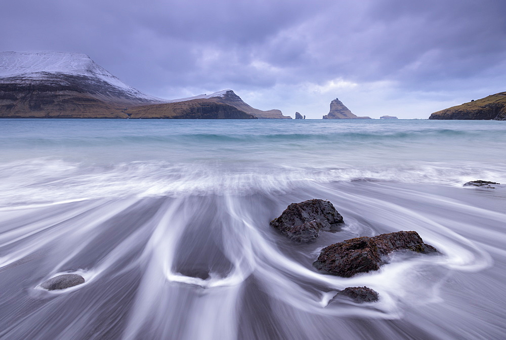 Waves crash onto the black sandy beach at Bour on the island of Vagar in the Faroe Islands, Denmark, Europe