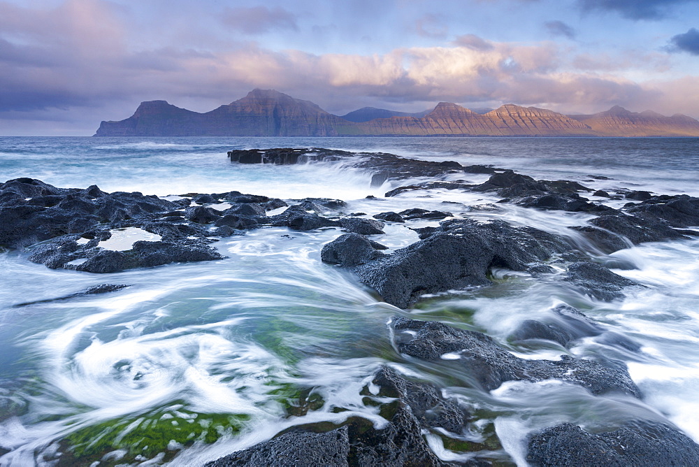 Waves crash against the rocky shores of Gjogv in the Faroe Islands, Denmark, Europe