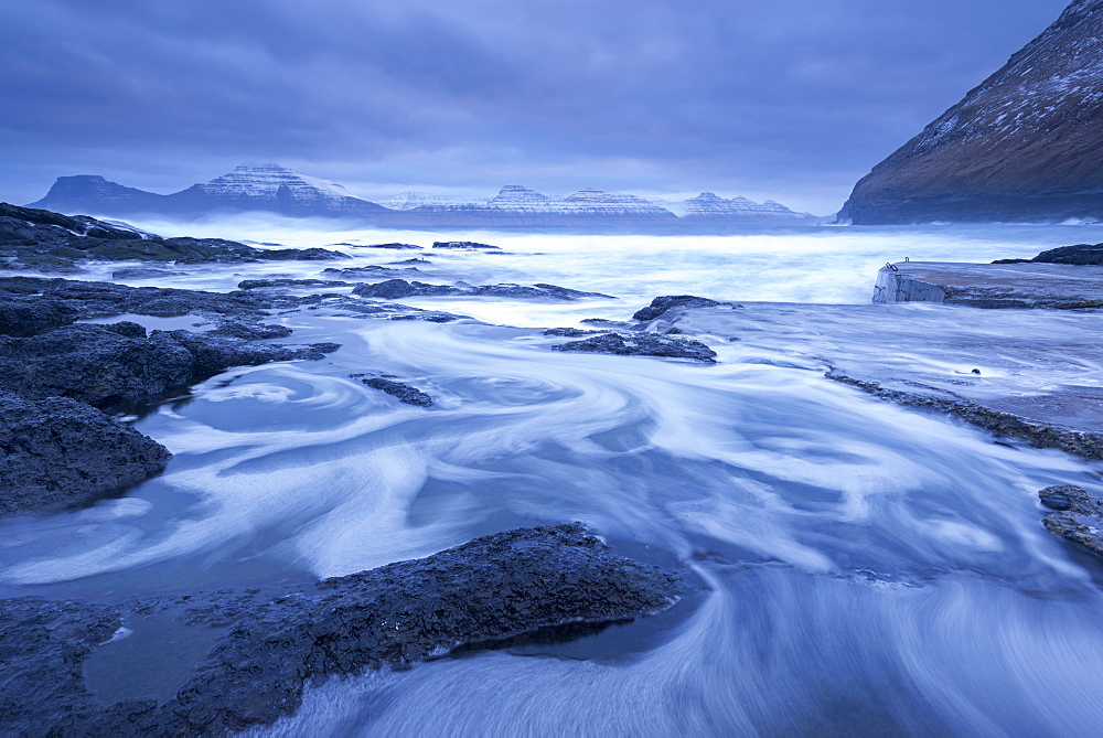 Atlantic waves swirl and crash over the rocky shores of Gjogv on the island of Eysturoy in winter, Faroe Islands, Denmark, Europe