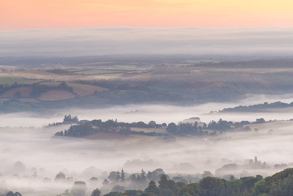 Mist floats over rolling countryside below Castle Drogo at dawn, Dartmoor, Devon, England, United Kingdom, Europe