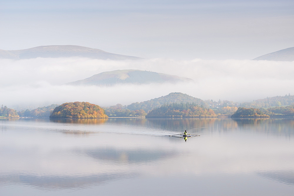 Single sculler rowing across a misty Derwent Water at dawn, Lake District National Park, Cumbria, England, United Kingdom, Europe