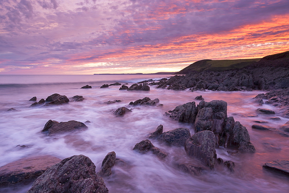 Colourful sunset over the rocky shores of Manorbier Beach, Pembrokeshire, Wales, United Kingdom, Europe