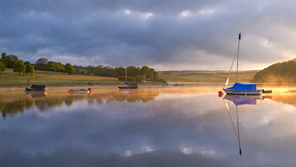 Boats on a reflective Wimbleball Reservoir at sunrise, Exmoor National Park, Somerset, England, United Kingdom, Europe