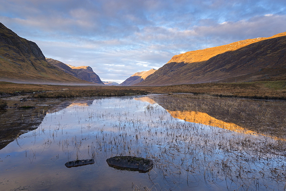 Sunlit mountains of Glencoe, reflected in the still waters of Lochan na Fola, Highlands, Scotland, United Kingdom, Europe