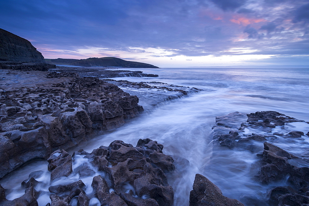 Waves surge over the rocky ledges of Dunraven Bay on the Glamorgan Heritage Coast in winter, Southerndown, Wales, United Kingdom, Europe