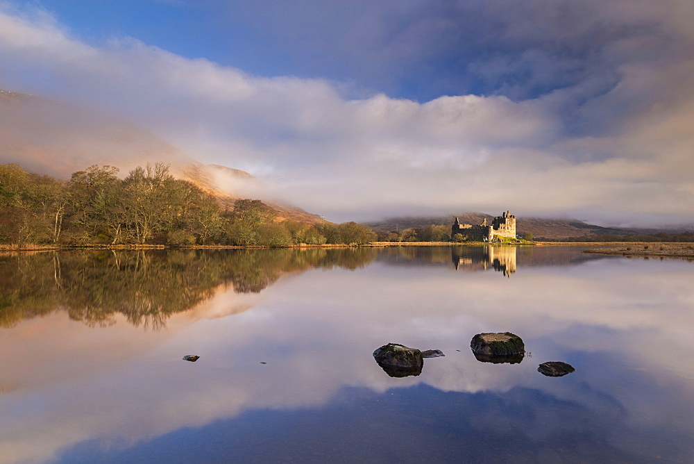 Rich morning sunlight illuminates Kilchurn Castle on a reflective Loch Awe, Argyll, Highlands, Scotland, United Kingdom, Europe