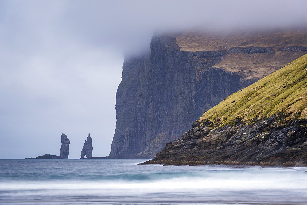 The sea stacks Risin og kellingin at the base of dramatic cliffs on Eysturoy in the Faroe Islands, Denmark, Europe