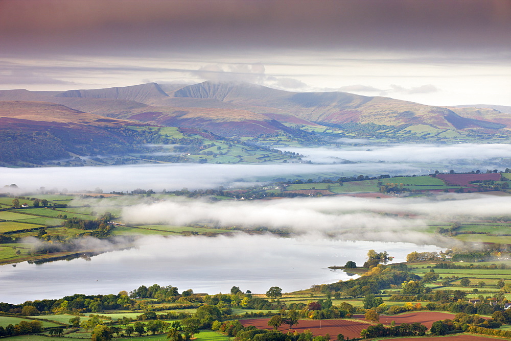 Pen Y Fan rises above a mist shrouded landscape near Llangorse Lake, Brecon Beacons National Park, Powys, Wales, United Kingdom, Europe