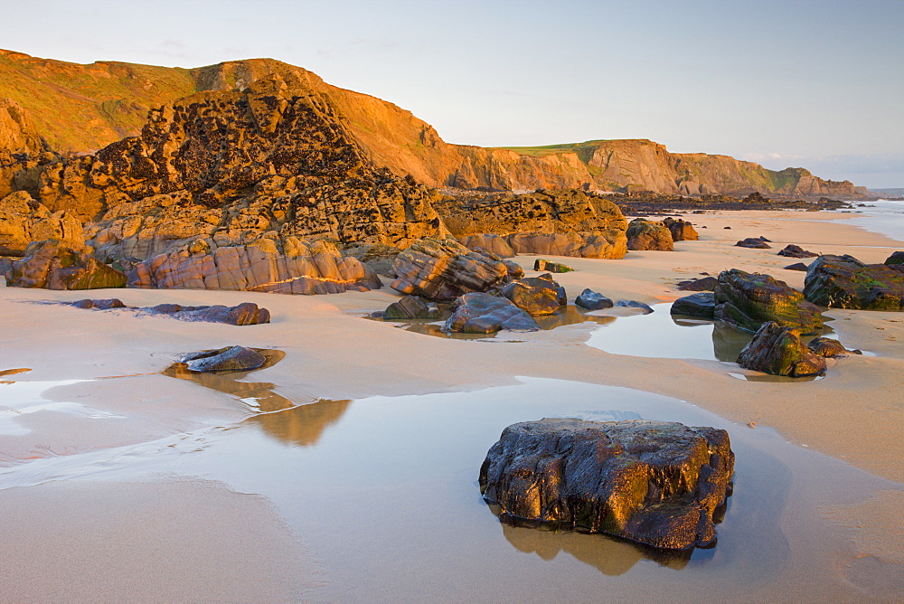 Golden evening light illuminates a deserted Sandymouth Bay in North Cornwall, England, United Kingdom, Europe