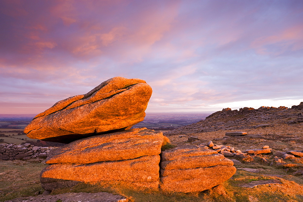 The first rays of early morning winter sunlight bathe a granite Logan Rock in a rich glow, Higher Tor, Dartmoor National Park, Devon, England, United Kingdom, Europe