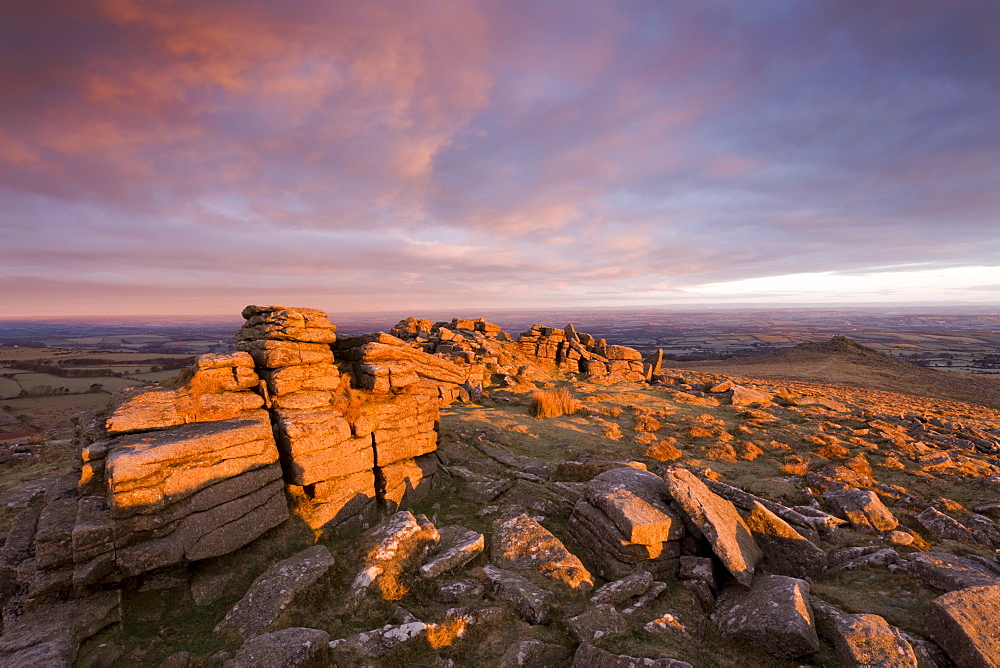 The first rays of early morning winter sunlight bathe Higher Tor in a rich glow, Dartmoor National Park, Devon, England, United Kingdom, Europe