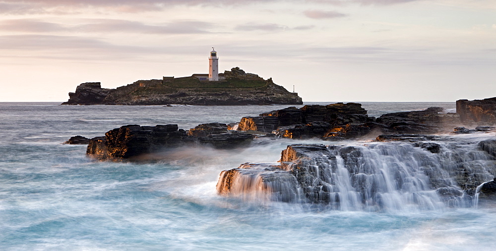 Waves crash over the rocks at Godrevy Point, looking out towards the lighthouse on Godrevy Island, Cornwall, England, United Kingdom, Europe