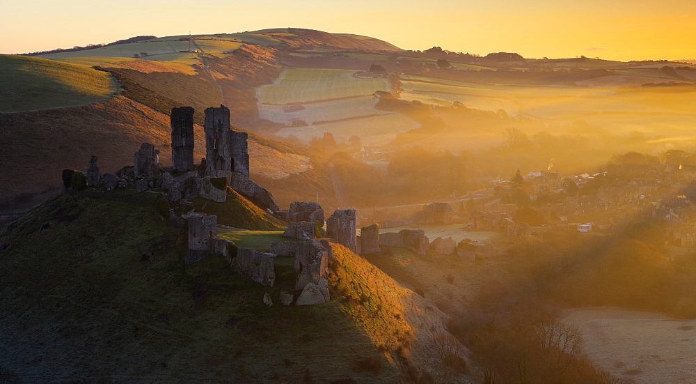 Misty winters sunrise over the village and castle at Corfe, Dorset, England, United Kingdom, Europe