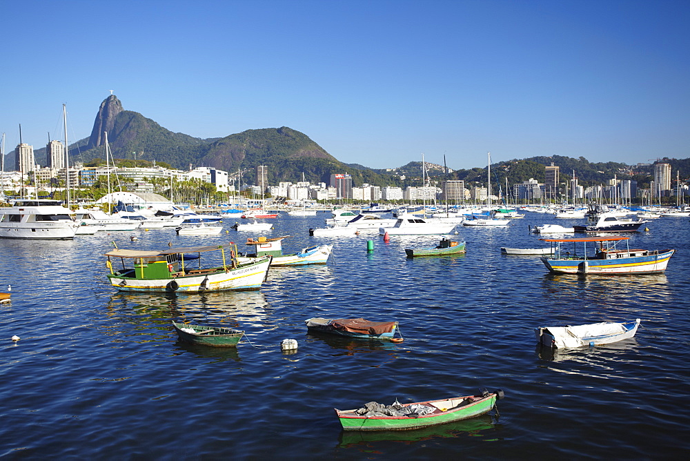 Boats moored in the harbour with Christ the Redeemer statue in background, Urca, Rio de Janeiro, Brazil, South America 