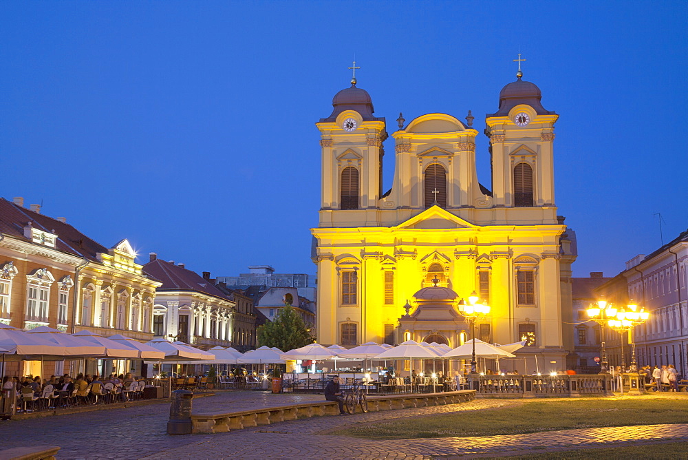 Roman Catholic Cathedral  and outdoor cafes in Piata Unirii at dusk, Timisoara, Banat, Romania, Europe 