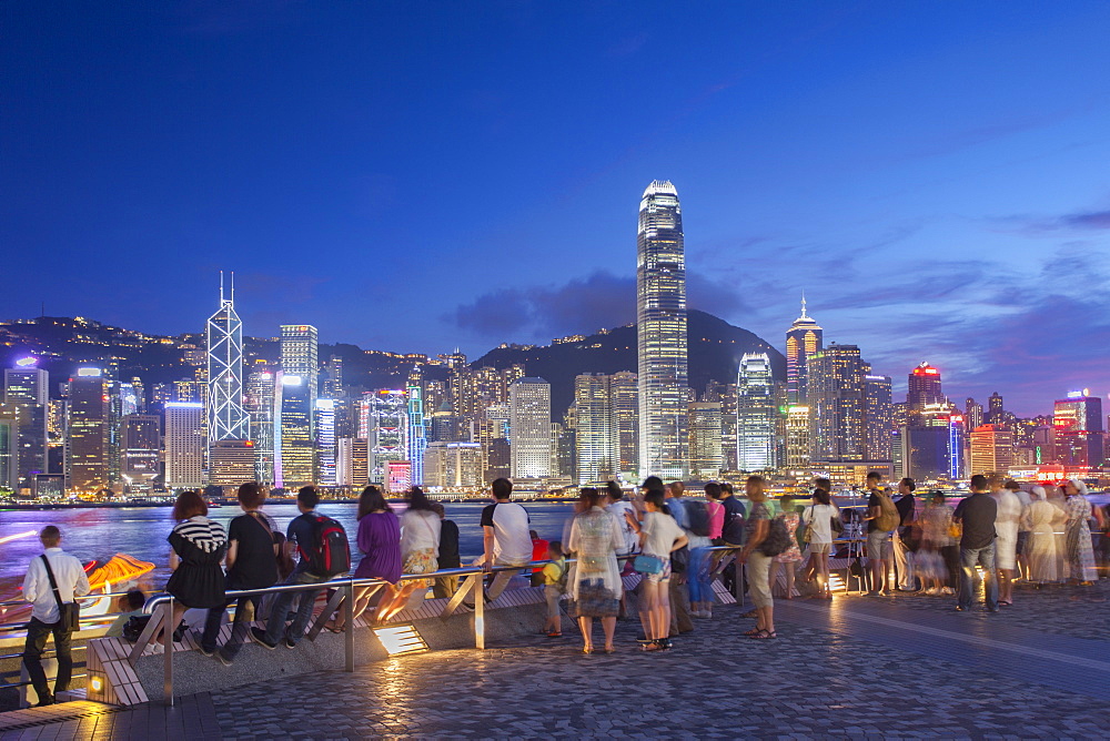 Tourists looking at Hong Kong Island skyline from Tsim Sha Tsui at dusk, Hong Kong, China, Asia