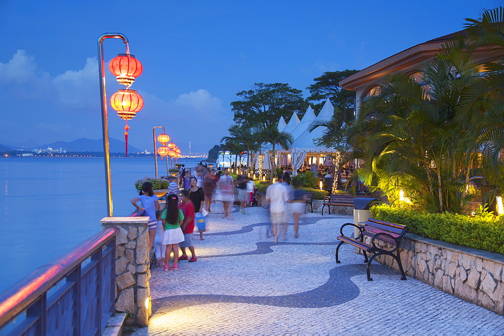 People walking along promenade at dusk, Discovery Bay, Lantau, Hong Kong, China, Asia