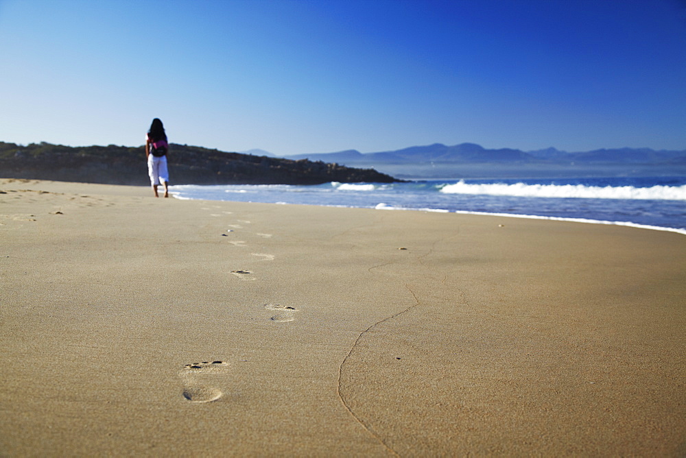 Woman walking on beach, Plettenberg Bay, Western Cape, South Africa, Africa