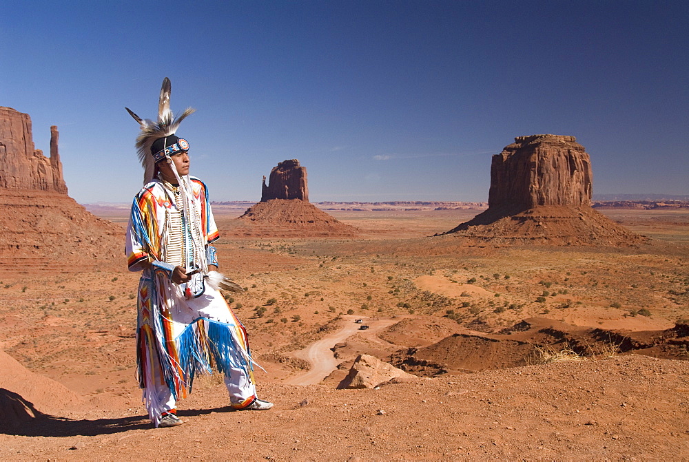 Navajo man dressed in traditional costume with Merrick Butte on the right and East Mitten Butte in the centre, Monument Valley Navajo Tribal Park, Utah, United States of America, North America