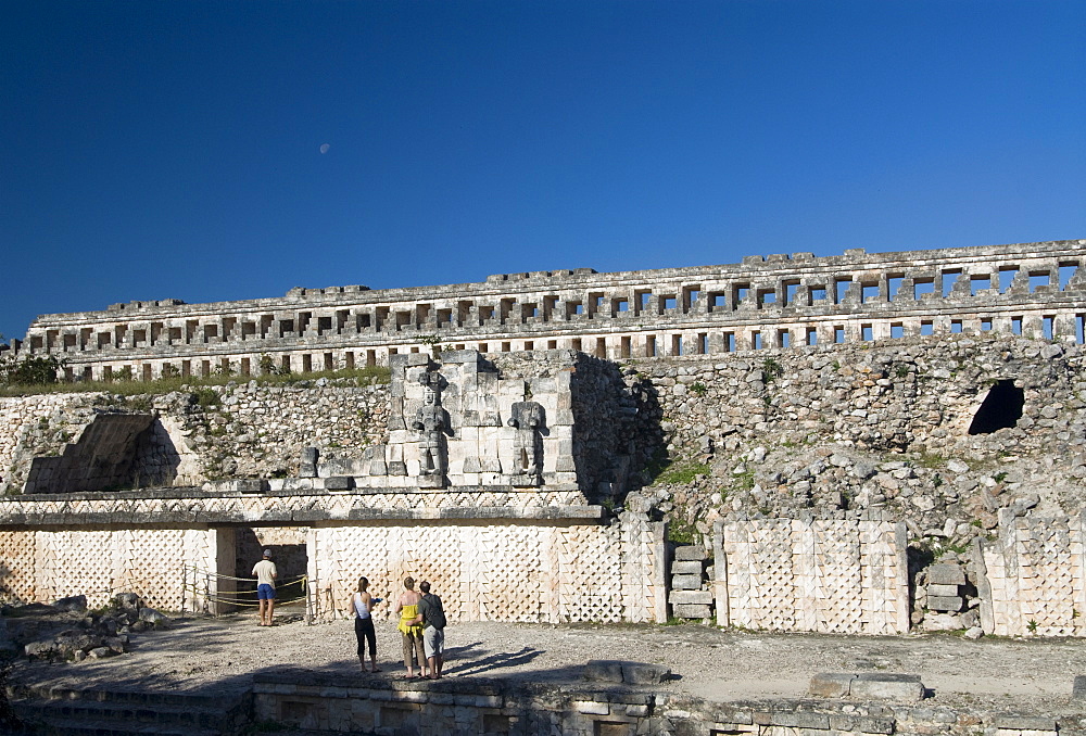 Tourists in front of the unusual restored Atlantes stone carved male figures at rear of the Palace of Masks, Kabah, Yucatan, Mexico, North America