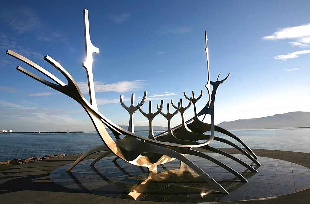 The midnight sun lights up the giant steel boat sculpture that stands on the water's edge at Reykjavik, Iceland, Polar Regions