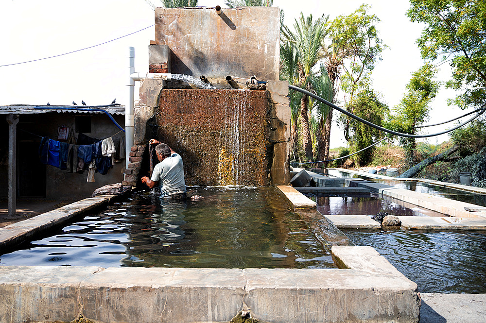 Man rinsing fabric of excess dye in factory well after block printing, before leaving in the sun to dry.