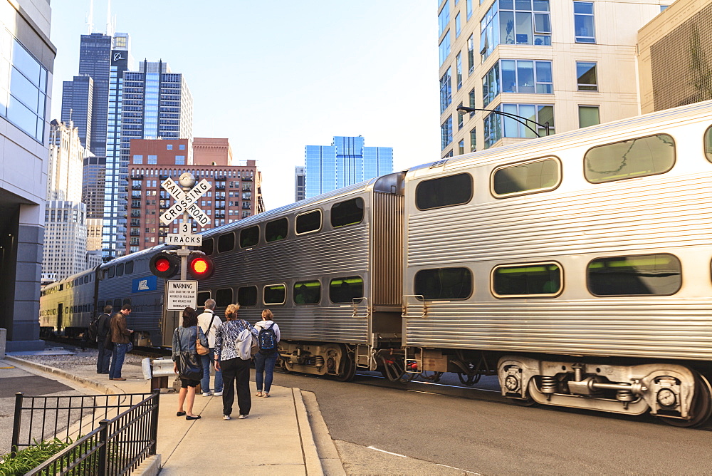 Metra Train passing pedestrians at an open railroad crossing, Downtown, Chicago, Illinois, United States of America, North America