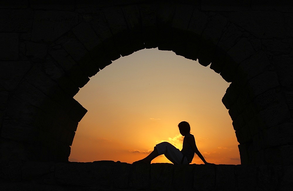 Girl watching sunset in Cesarea, Israel, Middle East