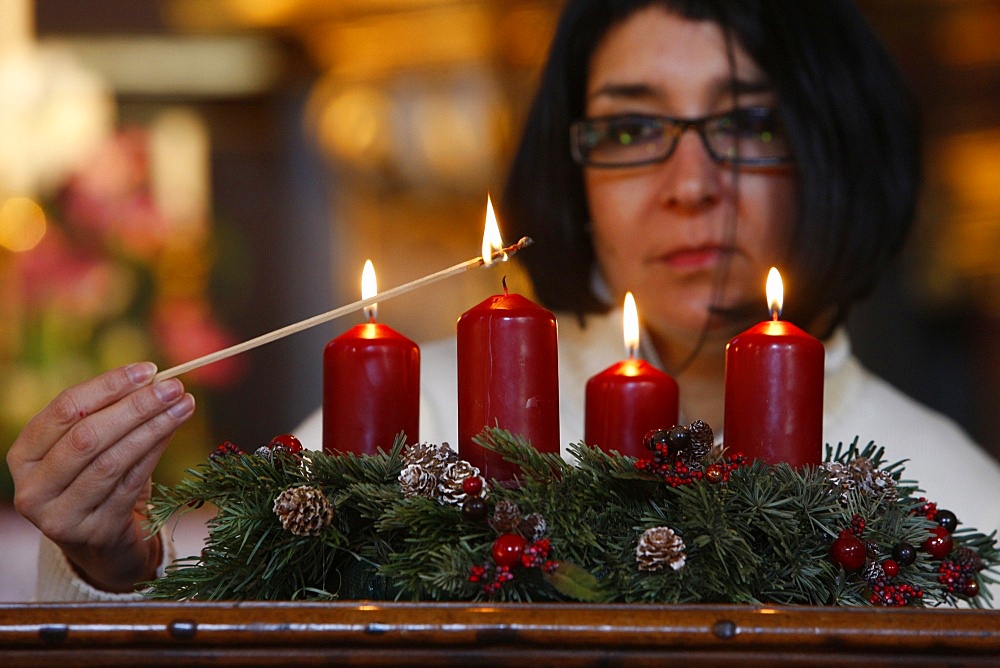 Woman lighting Advent candles, Saint-Nicolas de Veroce, Haute Savoie, France, Europe