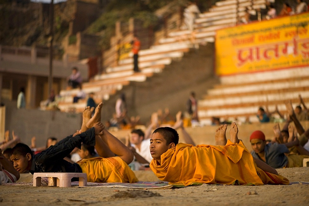 Students of Sanskrit school taking their daily yoga lesson at sunrise, on a ghat of Varanasi, Uttar Pradesh, India, Asia