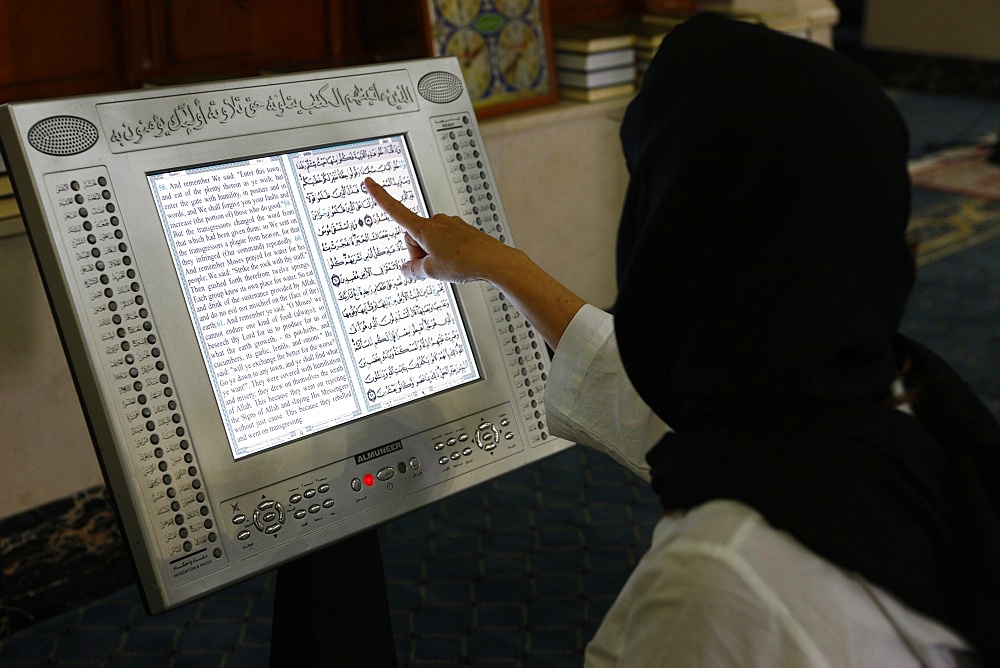 Woman reading an Arabic and English electronic version of The Holy Koran, Dubai, United Arab Emirates, Middle East