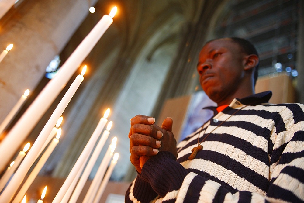 Man praying with candles in church, Amiens, Somme, France, Europe